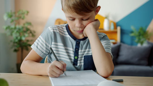 A boy sitting at a desk taking a written test