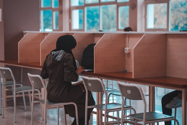 A UAE student sits at a library cubicle alone, hard at work.