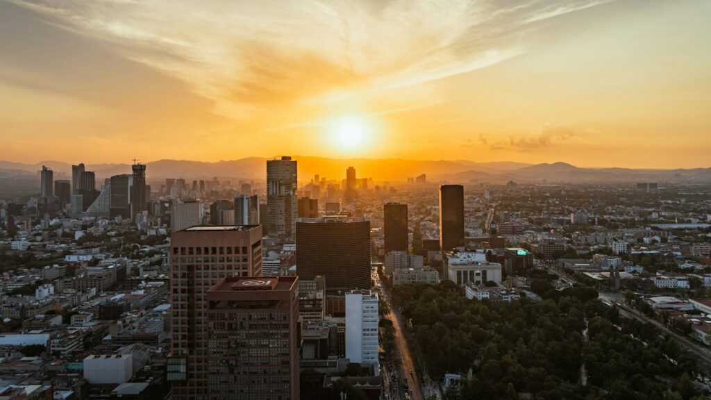 The Mexico City skyline at sunset, seen from above with mountains on the horizon