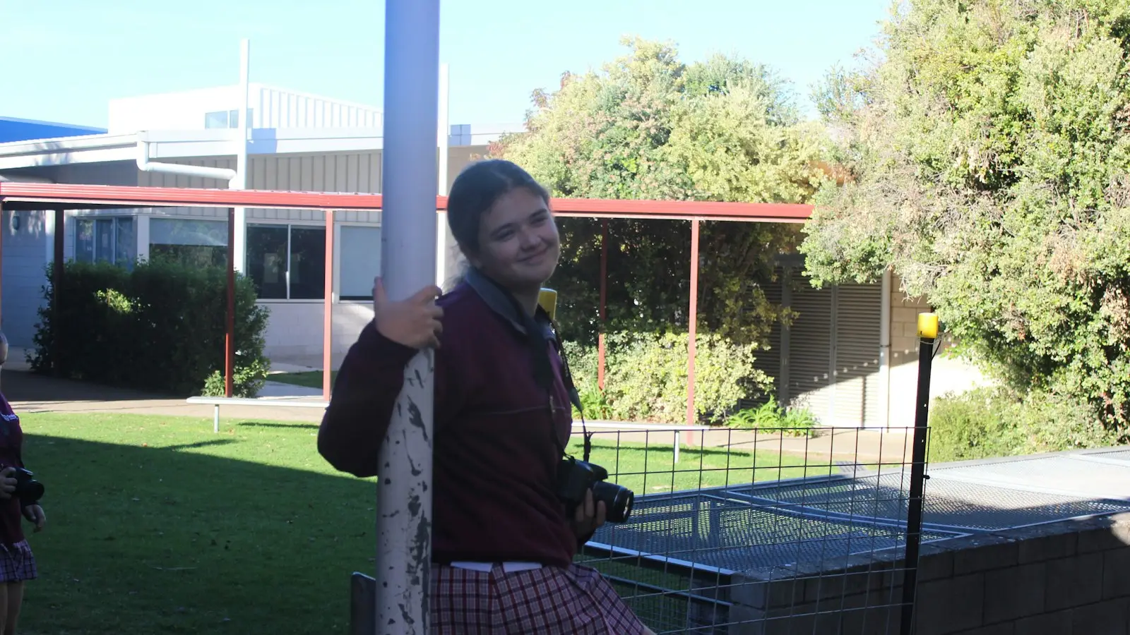 A smiling student in school uniform in the grounds of an Australian school