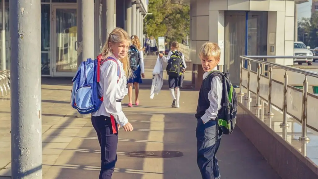 Children with backpacks walking into a school building