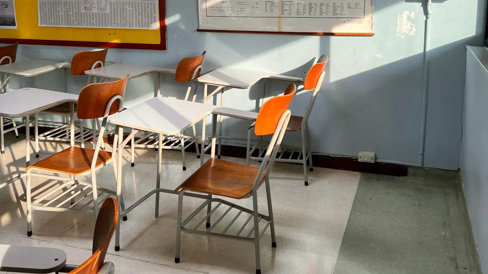 Empty classroom with world maps on the wall and chairs at desks