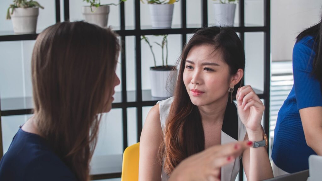Two colleagues in conversation at a table in a bright office