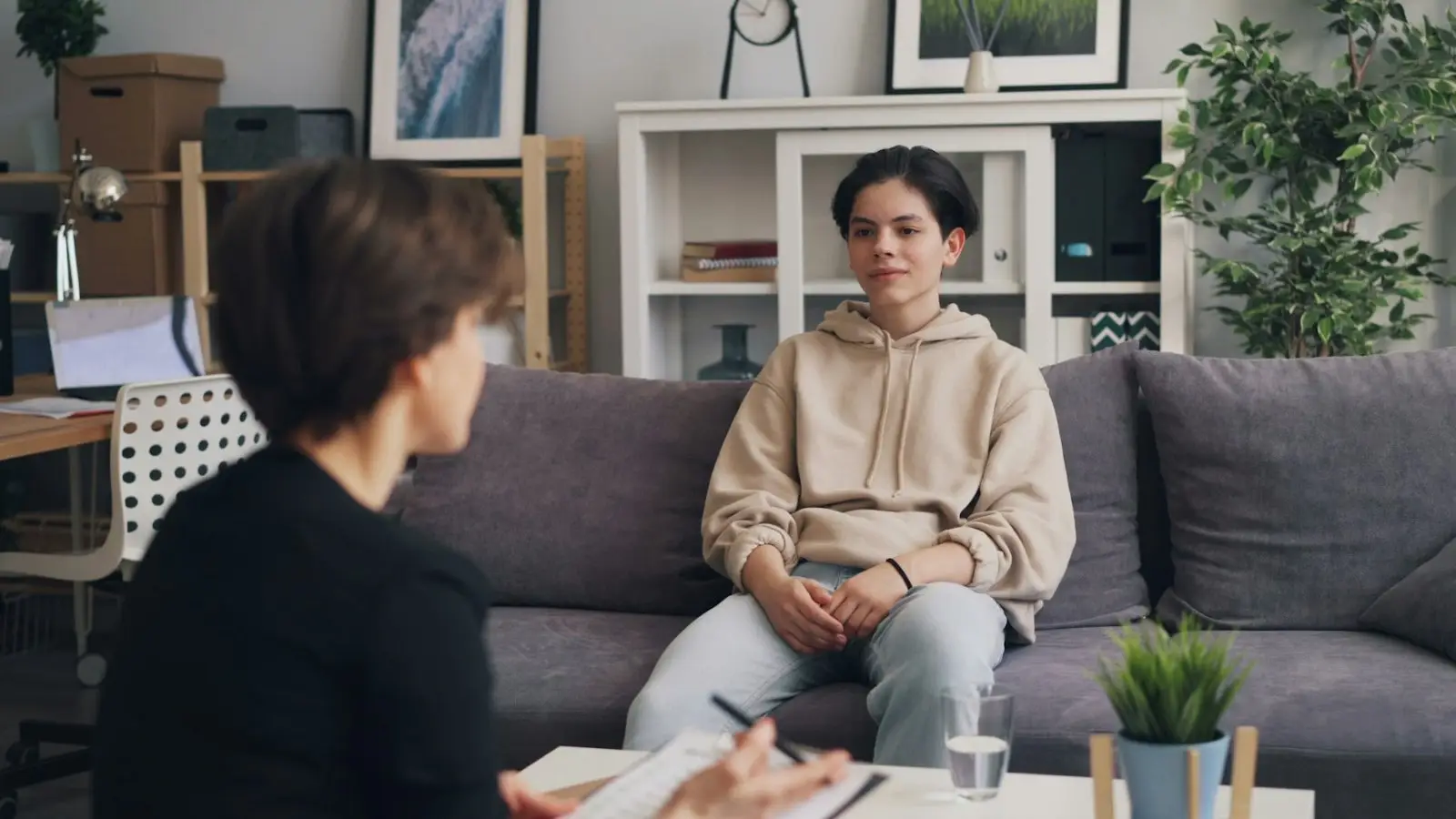 An adult and a teenager talking together on a sofa