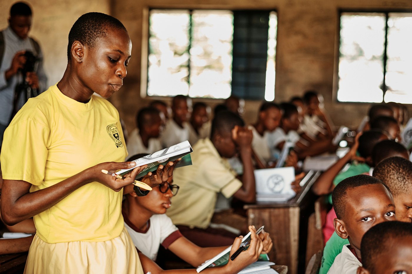 A young woman reads with a class of children at an education event in Nigeria