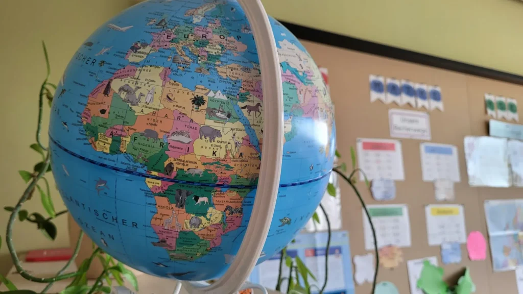 A globe on a classroom shelf in front of a bulletin board