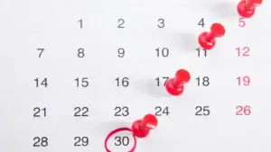 A wall calendar with red pins marking deadlines