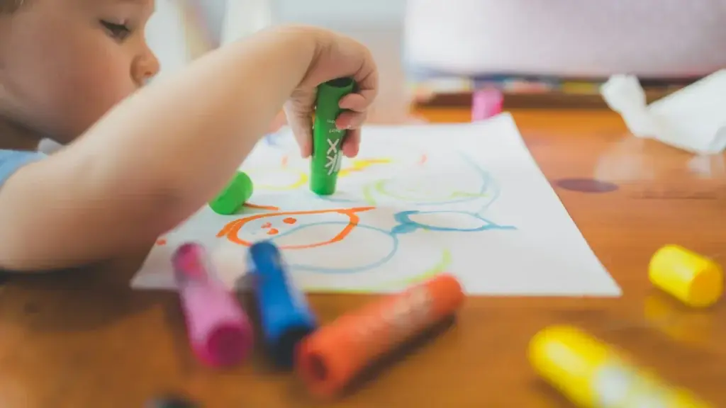 A young child drawing with crayons at a table