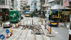 A Hong Kong street with tram tracks, a double-decker tram and a bus