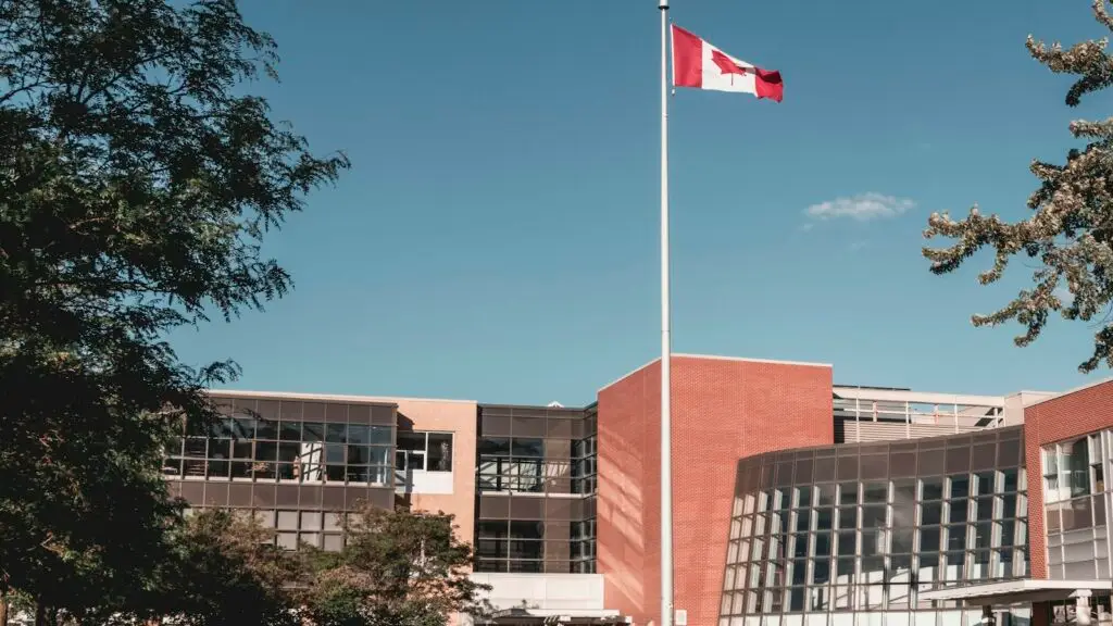 A public secondary school in Toronto with the Canadian flag flying outside; a family's address decides which public school a child is assigned to.